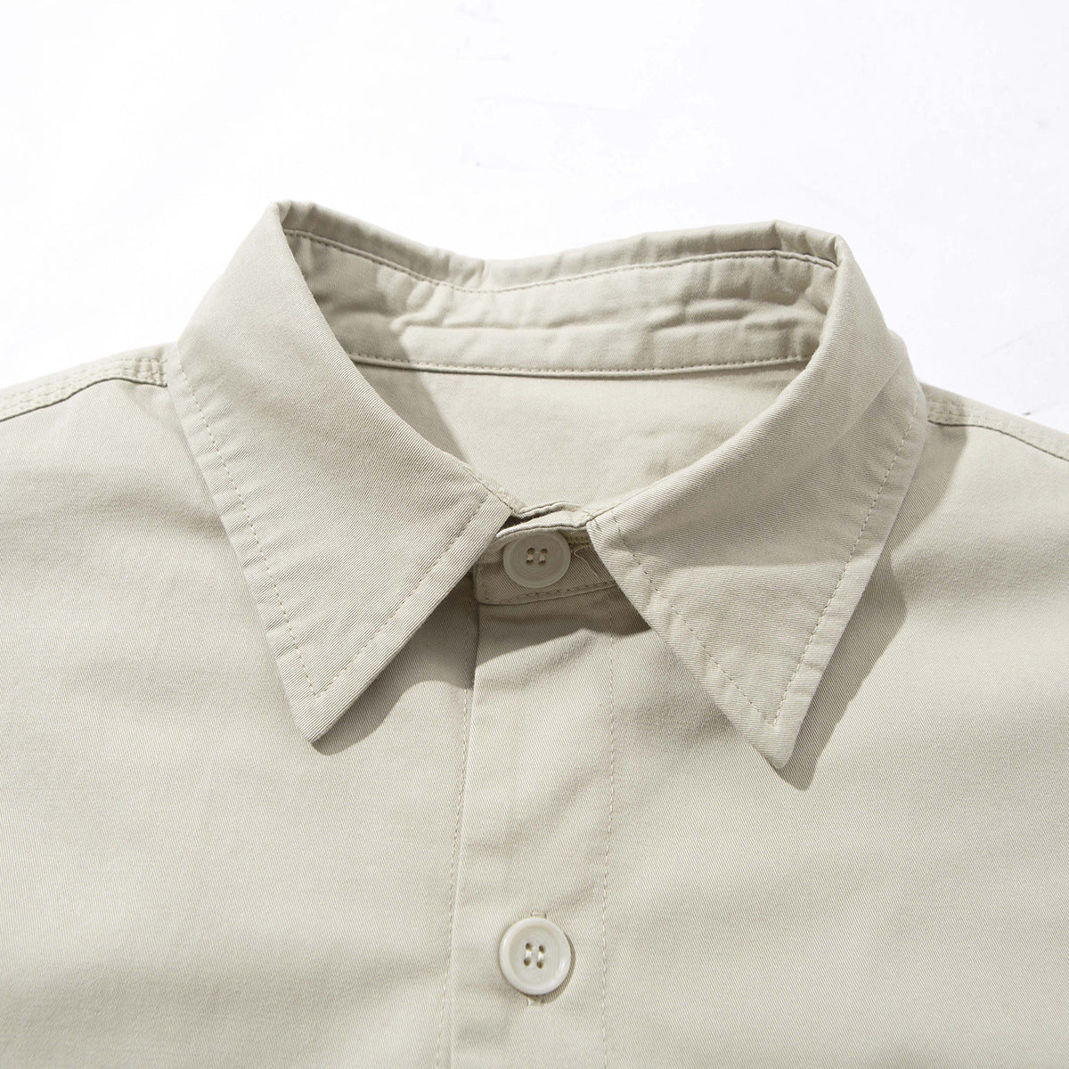 Close-up of a light beige collared jacket showing the front placket and buttons.