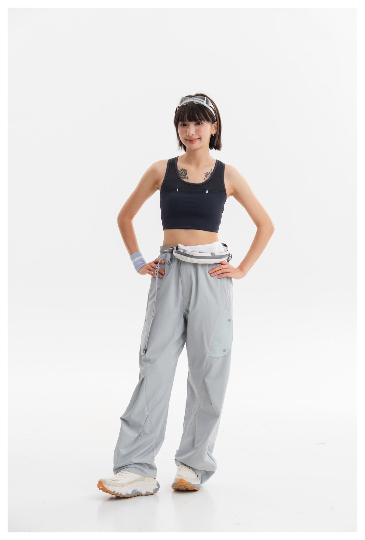 Full-length model in a navy cropped tank and pale blue-gray cargo pants, posing with hands on hips.