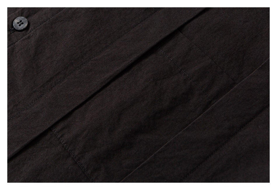 Close-up of a dark garment showing a button, front seam, and pocket opening.