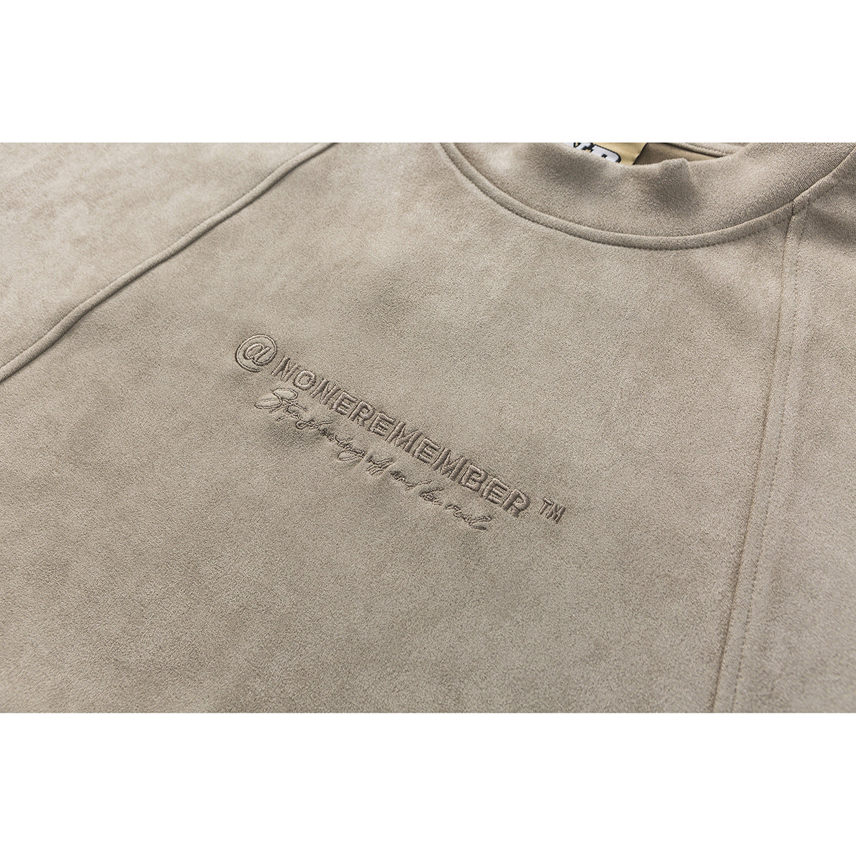 Close-up of a taupe crewneck sweatshirt with embroidered lettering on the chest.
