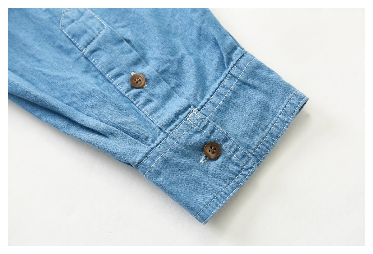 Light blue shirt sleeve cuff with a brown button and visible topstitching.
