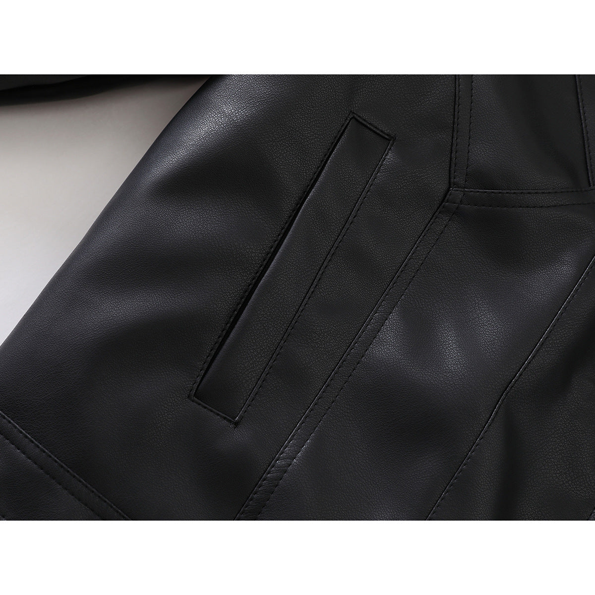 Close-up of a black jacket's angled welt pocket and stitched panel seams.