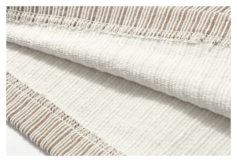 Close-up of the inside of cream and brown striped fabric, showing a white stitched seam and folded edge.