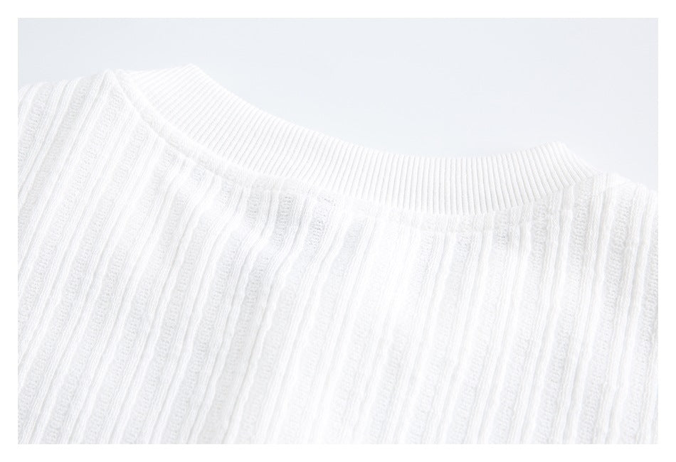 Close-up of a white ribbed crew neckline and vertically textured knit fabric.