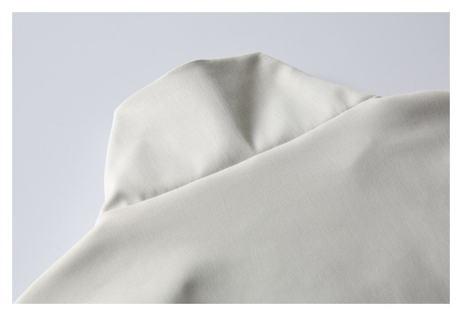 Close-up of light beige garment fabric with a curved folded edge and visible seam.