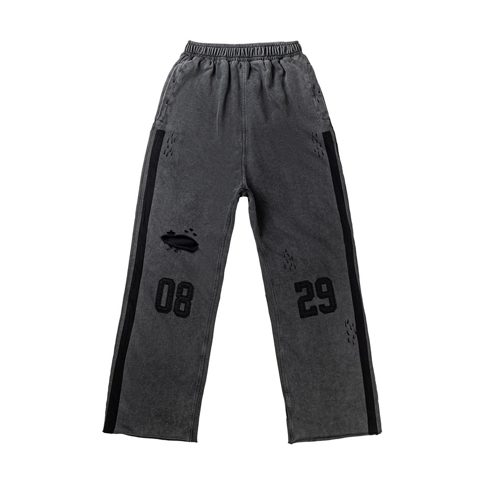 Front of washed dark gray wide-leg sweatpants with black side stripes, 08 and 29 numerals and distressed details