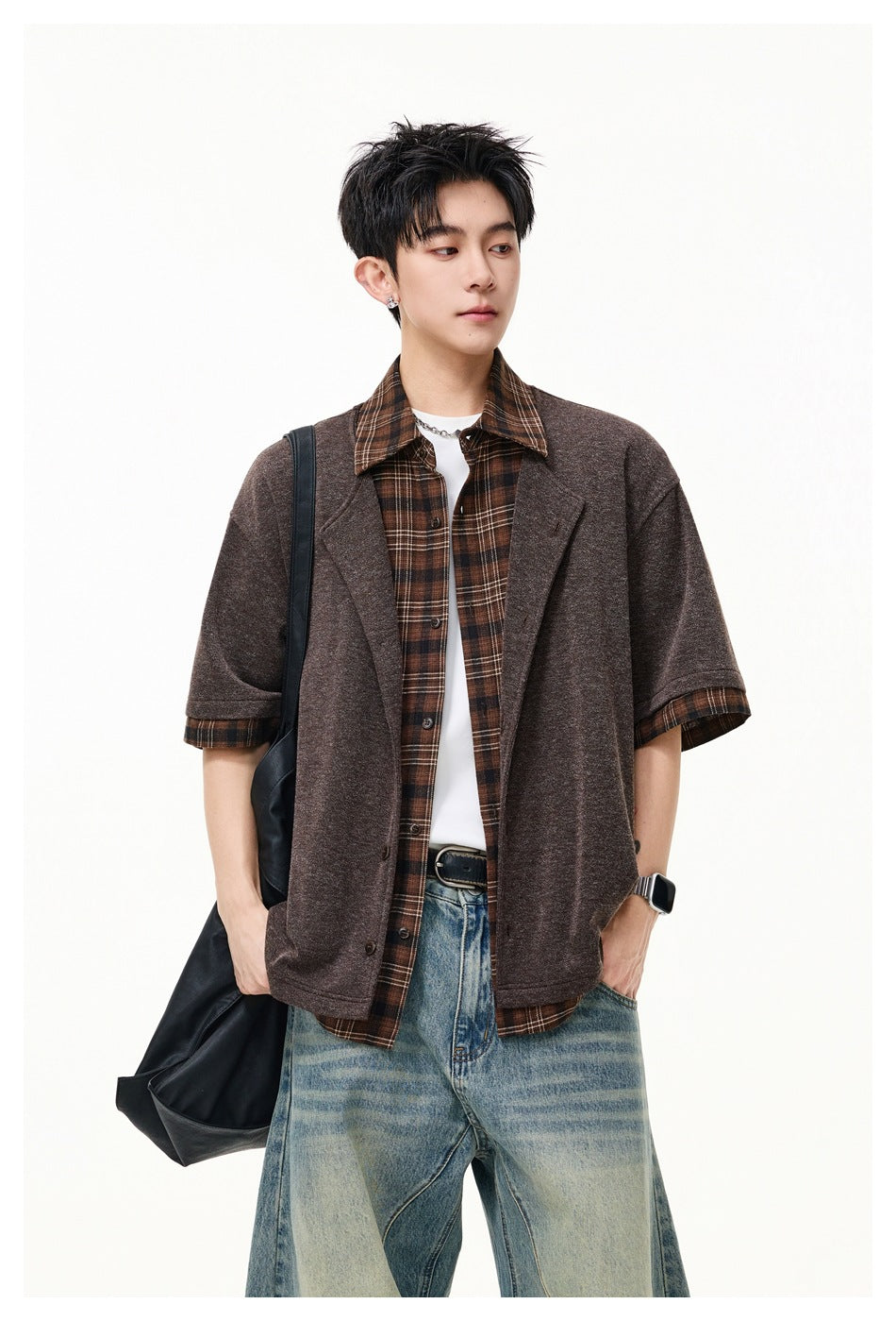 Model wearing an open brown short-sleeve lapel jacket over a brown plaid shirt and white tee.