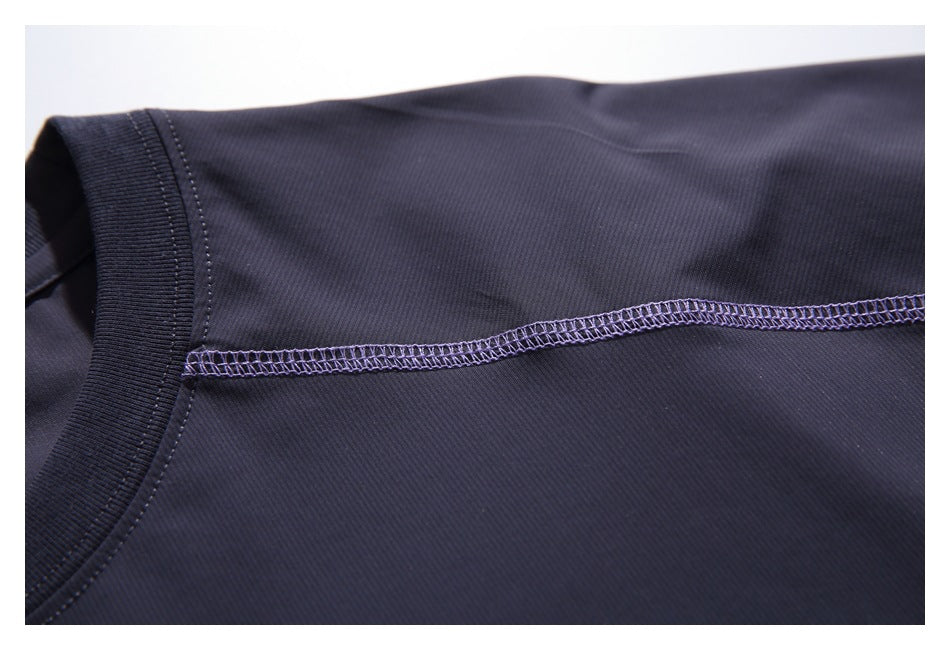 Close-up of the dark navy T-shirt shoulder and crew neckline with a purple overlock seam.