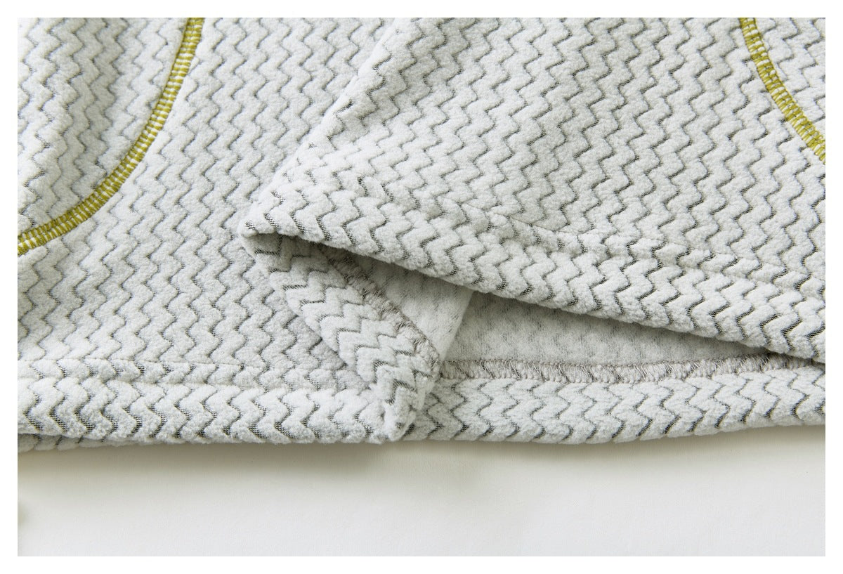 Close-up of overlapping panels and seam construction on light gray zigzag-patterned fabric with yellow stitching.