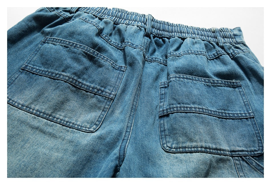 Close-up of the back of blue denim bottoms with an elastic waistband and two patch pockets.