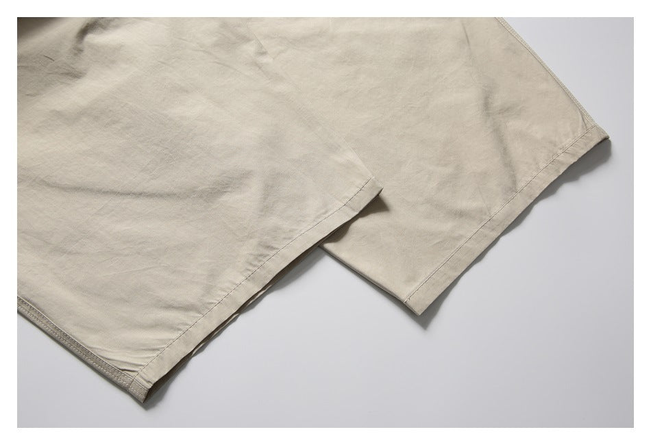 Close-up of the beige shorts' stitched hems and overlapping leg openings.
