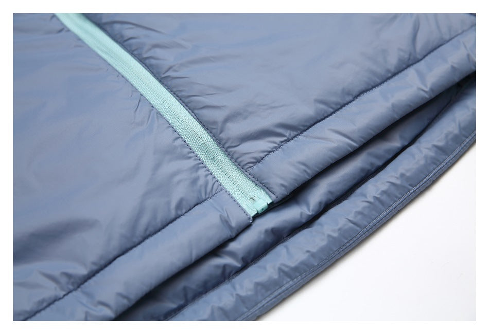 Close-up of the pale aqua zipper ending above the stitched hem of the slate-blue padded jacket.