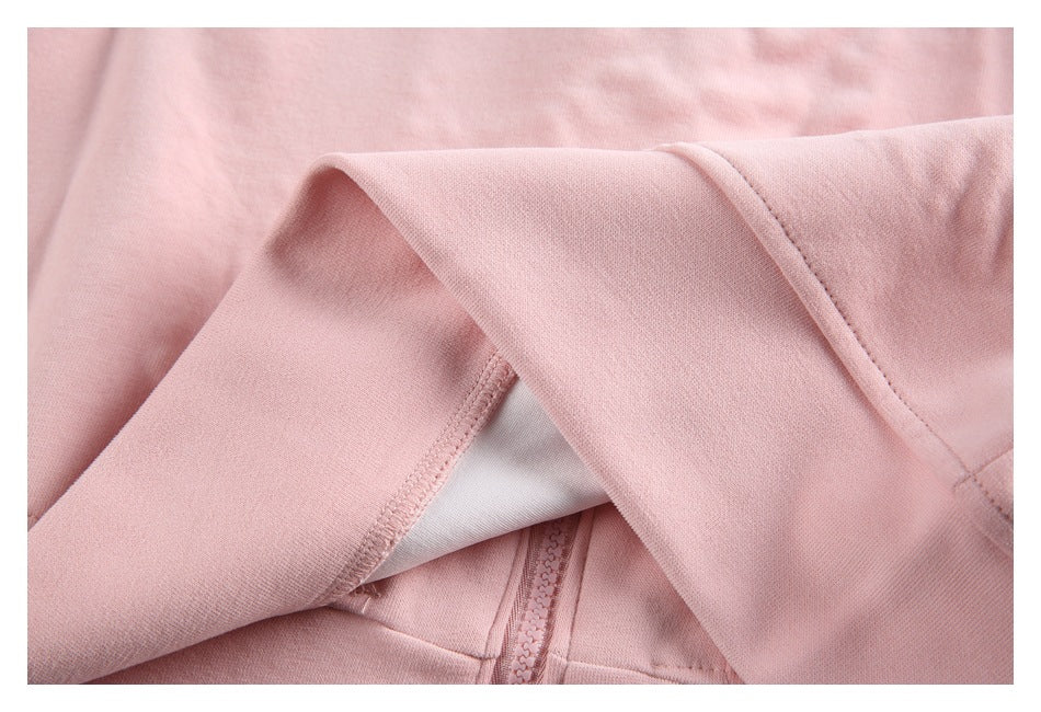 Close-up of pale pink hoodie fabric, stitching, a sleeve cuff, and part of the zipper.