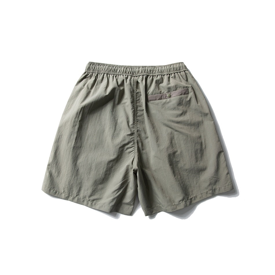 Back view of sage gray shorts with an elastic waistband and a small buttoned pocket.