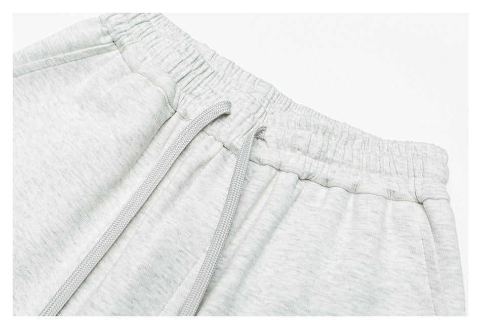 Close-up of gray pants showing the gathered elastic waistband and long drawstring.