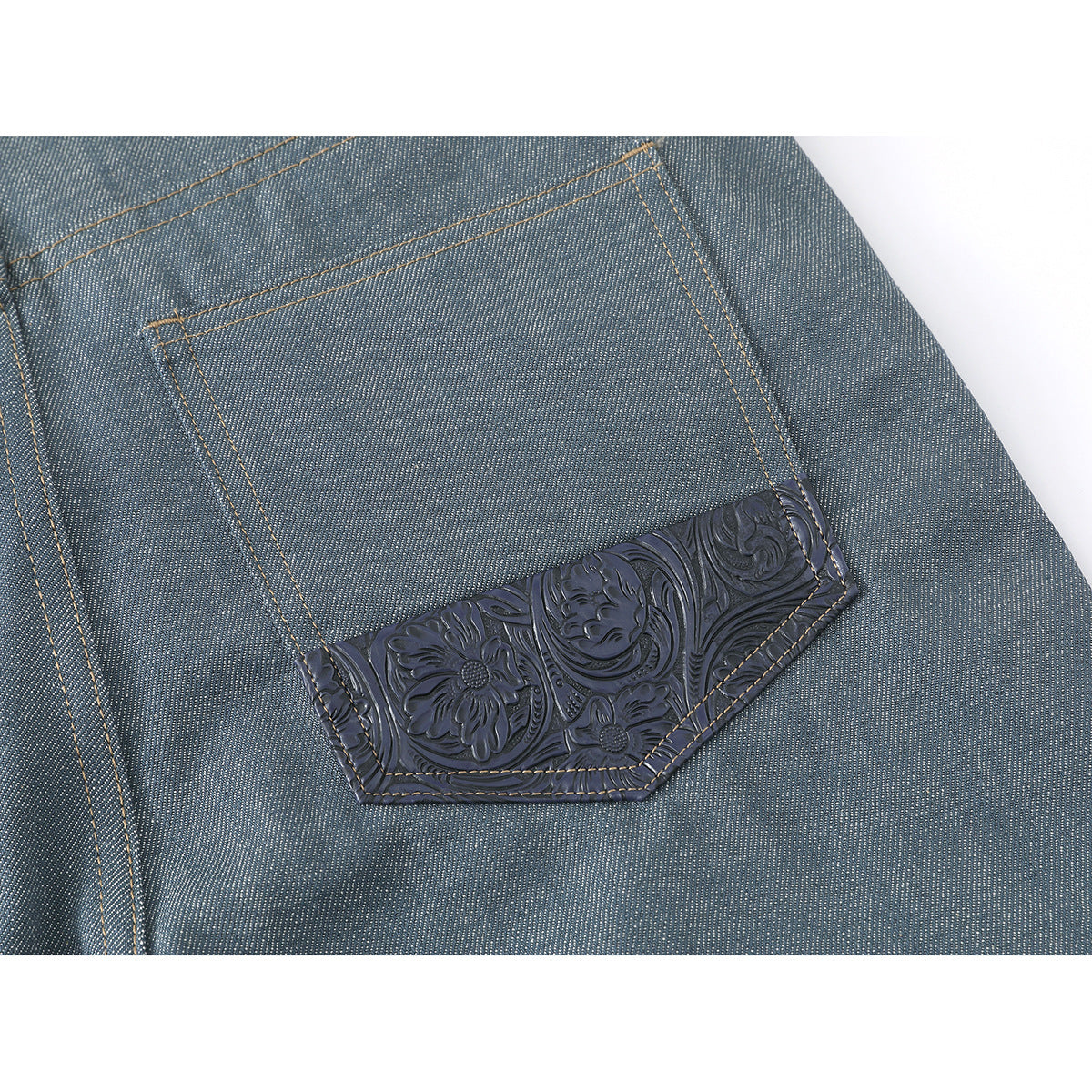 Close-up of a blue-gray jeans back pocket with a dark embossed floral-patterned lower panel.
