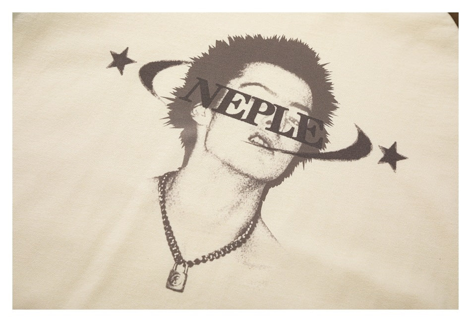 Close-up of an ivory garment's dark portrait-and-stars print with English lettering across the face.