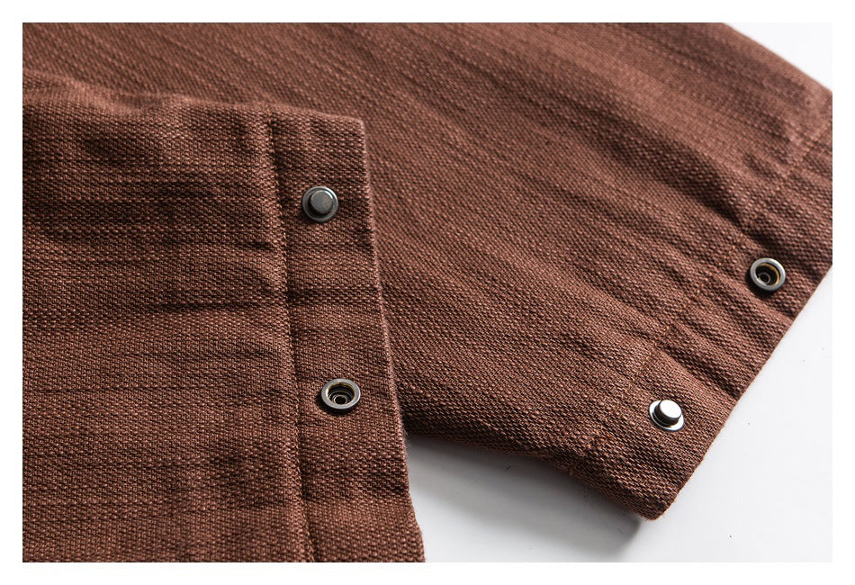 Close-up of a brown garment cuff with dark metal snap buttons and textured fabric.