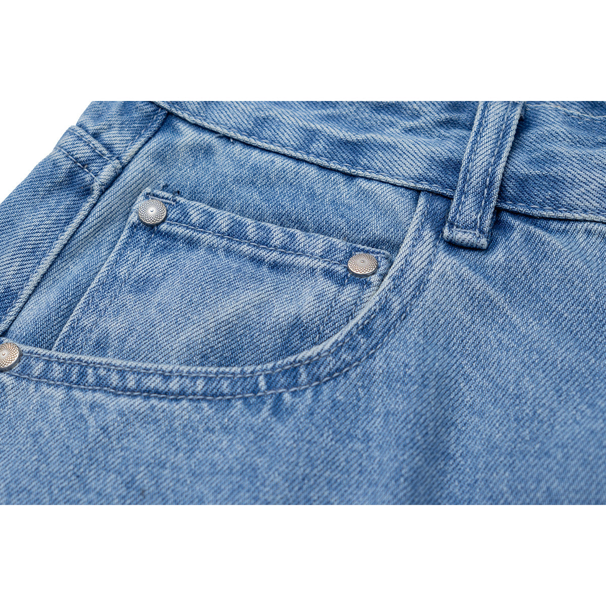 Close-up of a light blue jeans front pocket with small metal rivets and a belt loop.