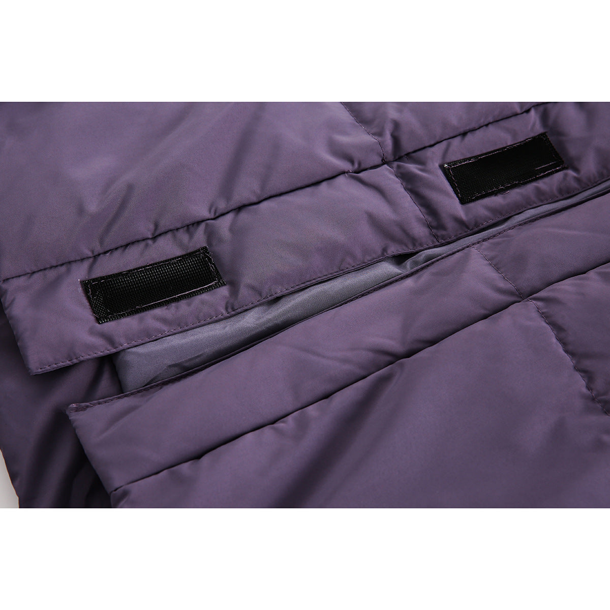 Close-up of two black hook-and-loop patches on the inside of a purple quilted jacket.