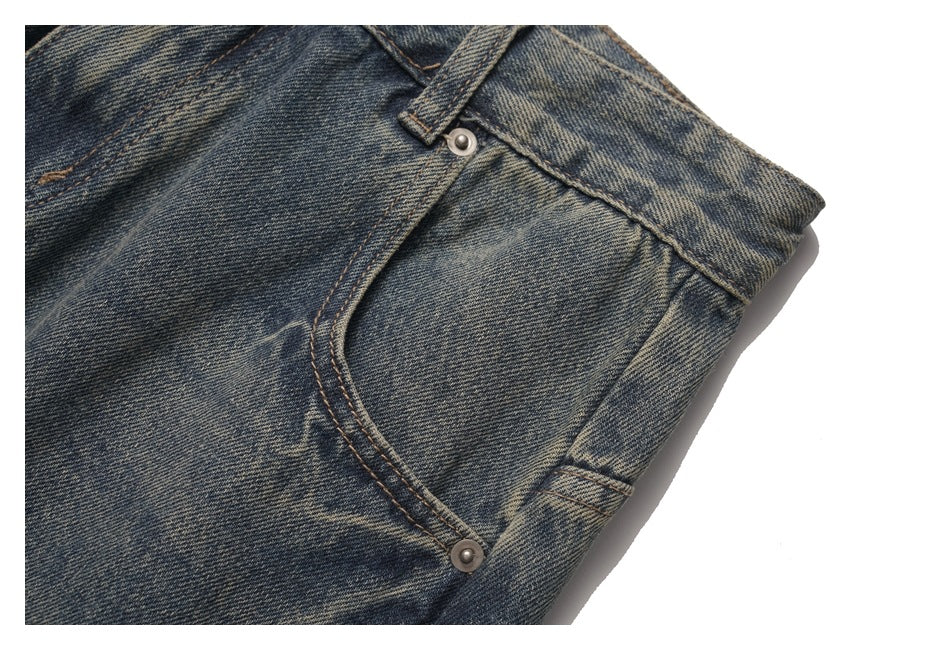 Close-up of a curved side pocket, rivets, and belt loop on faded dark blue jeans.