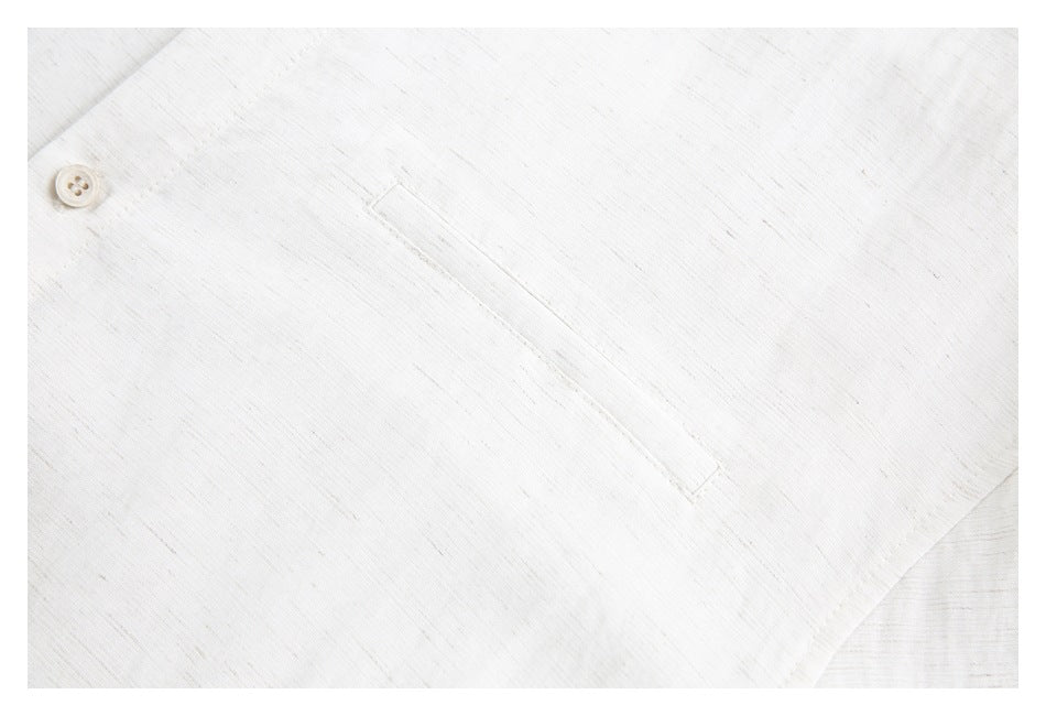 Close-up of an off-white shirt's chest pocket and a button on the front.