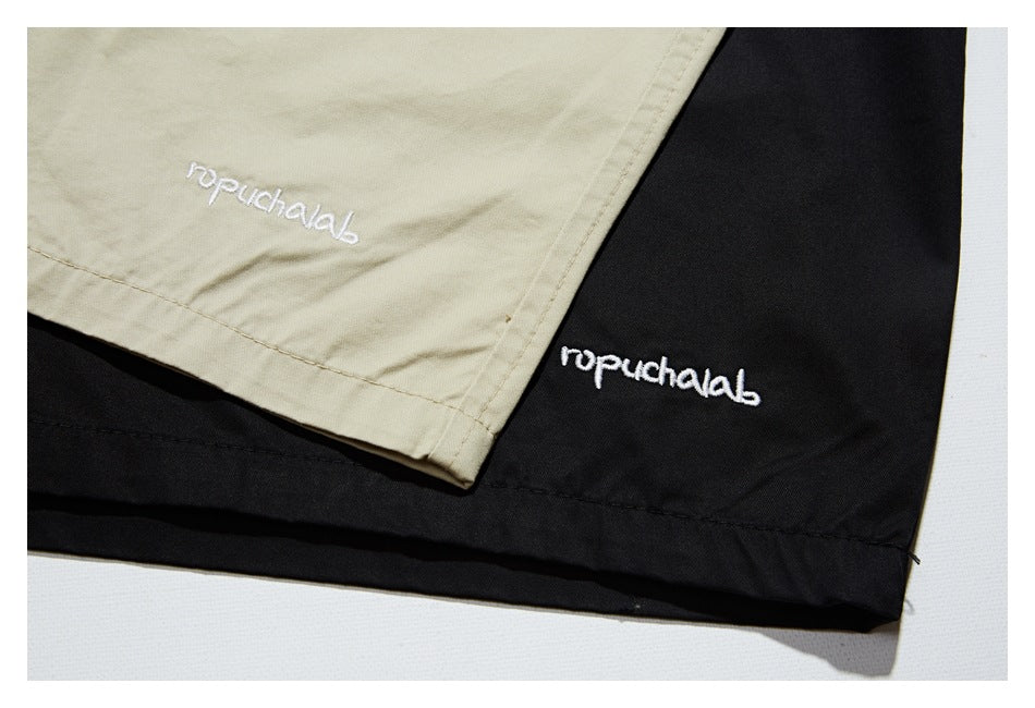 Close-up of beige and black garment hems with small white embroidered lettering.