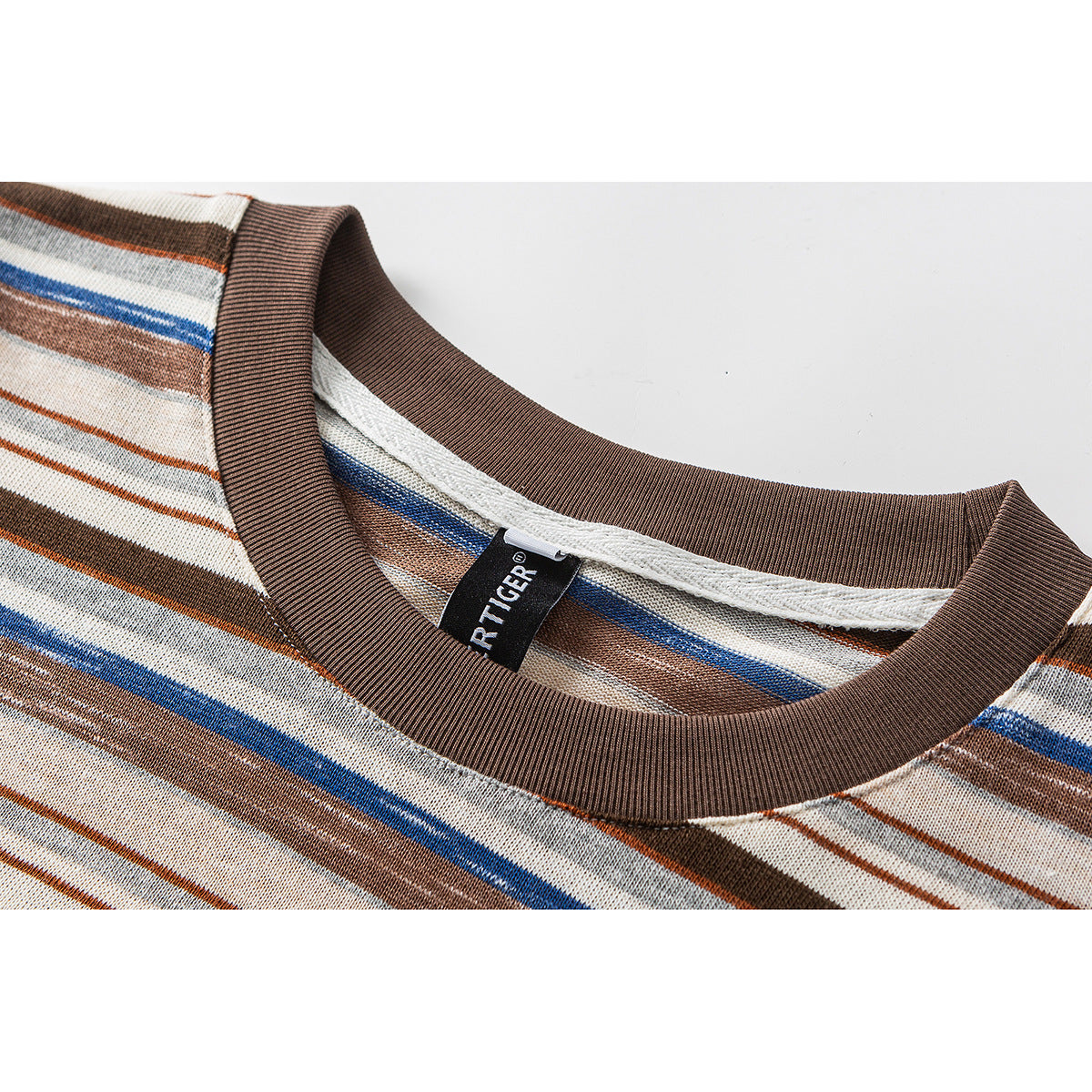 Close-up of a brown ribbed crew neckline on a cream shirt with brown, gray, and blue stripes; a sewn-in label is visible.