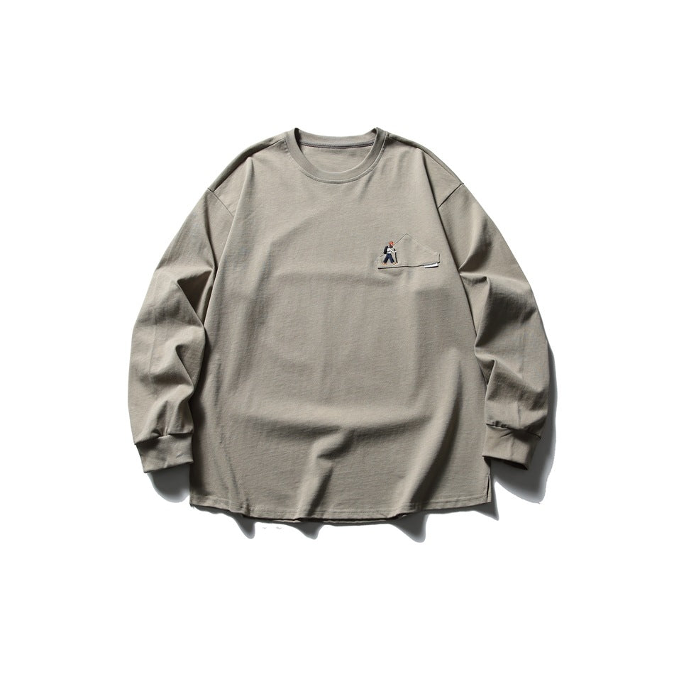 Gray-green long-sleeve crew neck tee flat lay with a small embroidered hiker motif on the chest