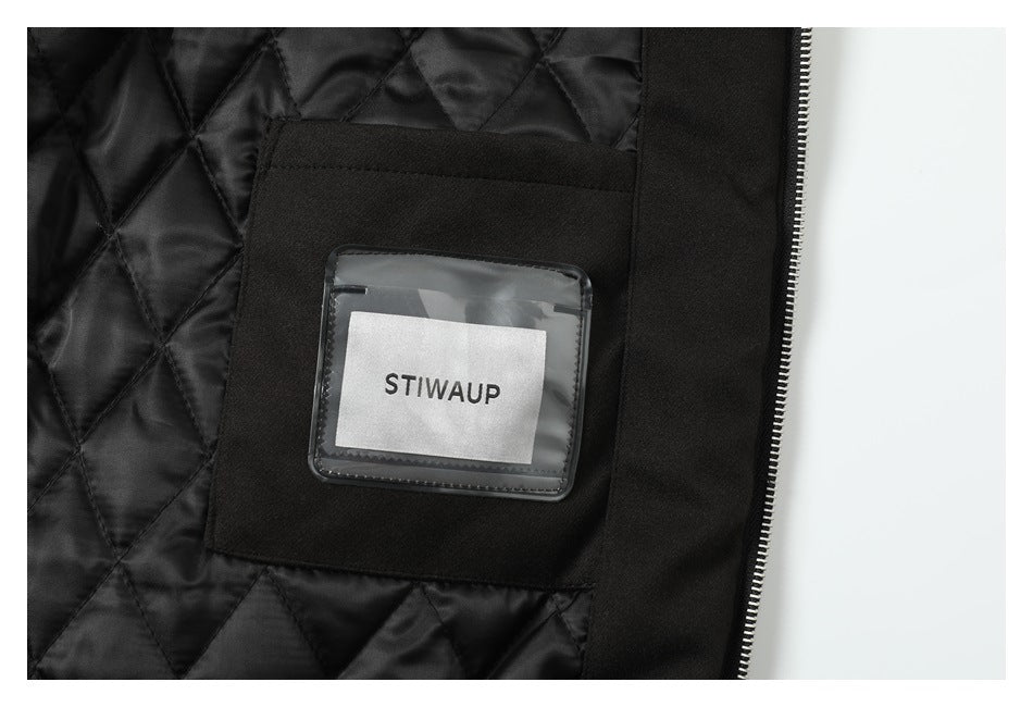 Close-up of a black jacket's quilted lining, inner pocket and zipper, with a STIWAUP label in a clear holder.