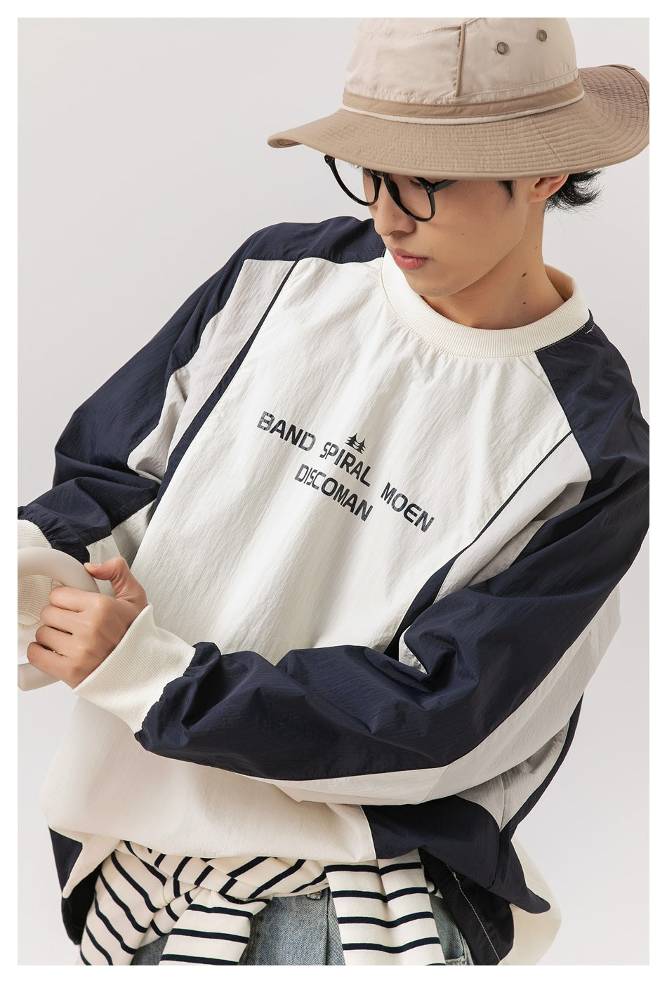 Close-up of the ivory top's black chest lettering, ribbed neckline and cuffs, and contrasting navy sleeves.