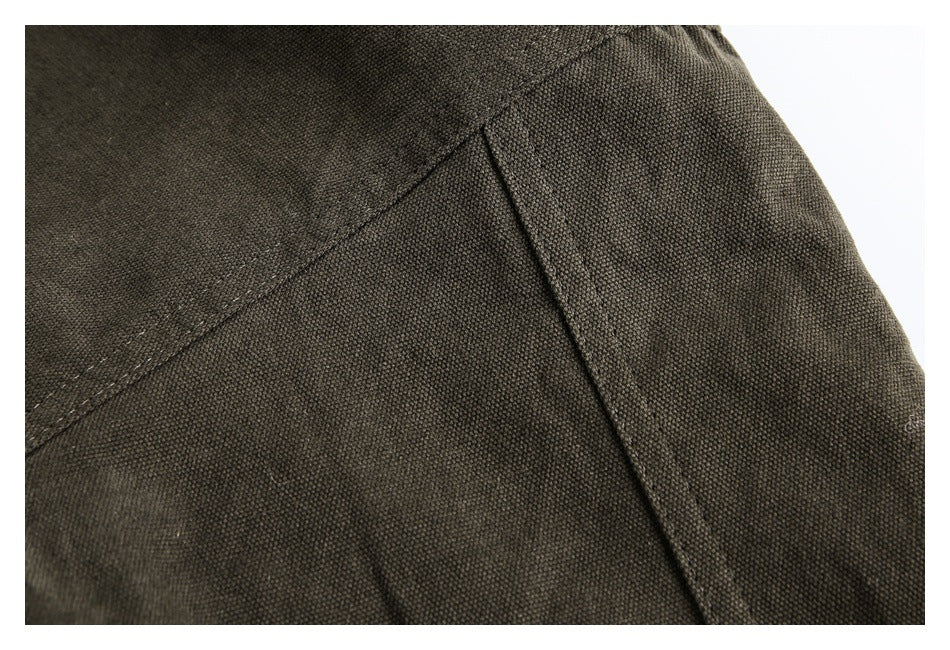 Close-up of dark olive-brown fabric showing a diagonal seam and narrow stitched panel.