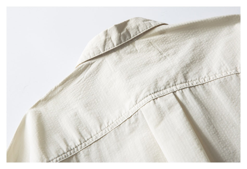 Close-up of an ivory shirt's collar and back shoulder yoke with a narrow pleat.