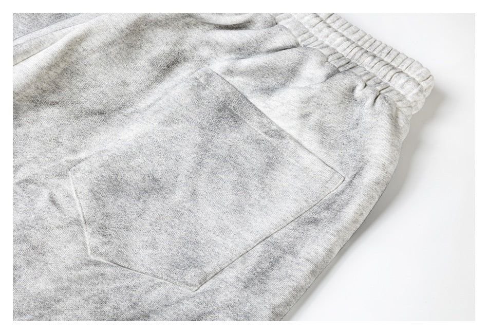 Close-up of a large stitched pocket on light gray shorts, with the elastic waistband visible.