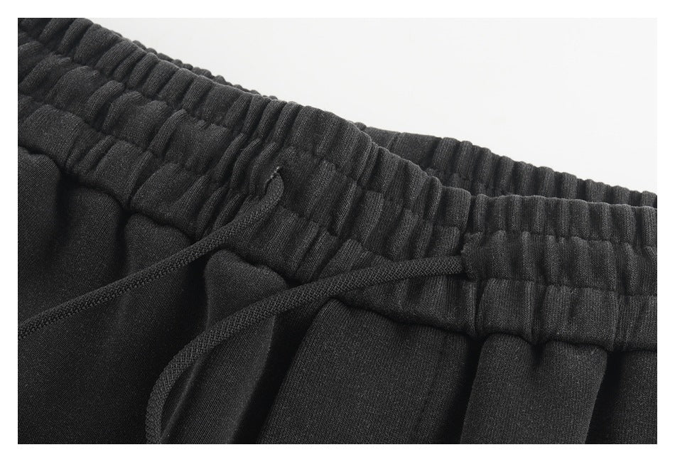 Close-up of black jogger pants with a gathered elastic waistband and matching drawstring.