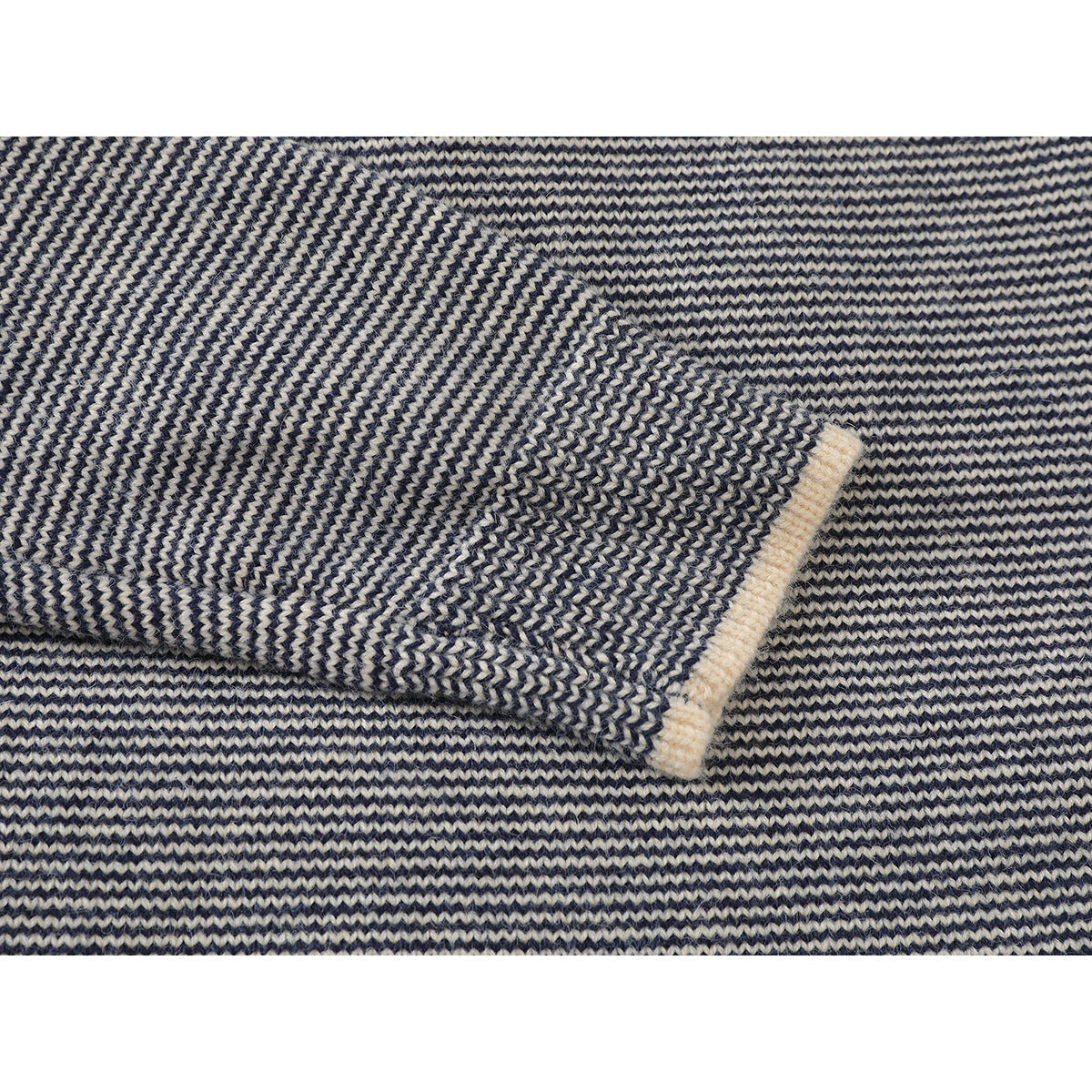 Close-up of a navy and cream knit sweater sleeve cuff with a cream ribbed edge.