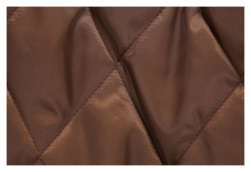 Close-up of brown fabric with large diamond-shaped quilted panels and visible stitching.
