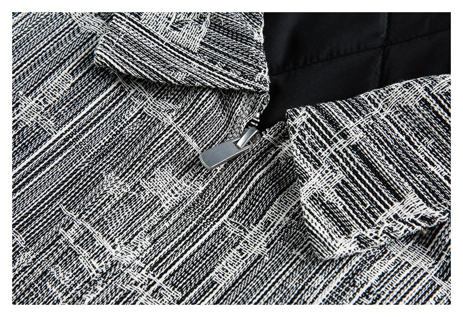 Close-up of black-and-white textured fabric with a silver zipper and overlapping garment panels.