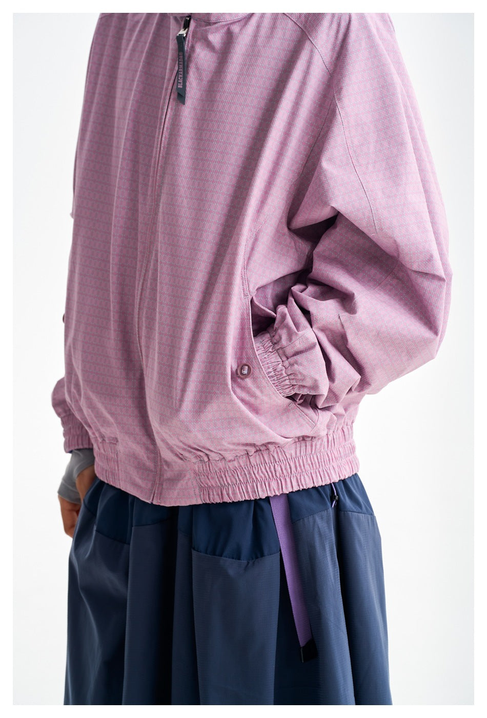 Close-up of the pink jacket's subtle pattern, gathered hem and cuff, pocket, and zipper pull.