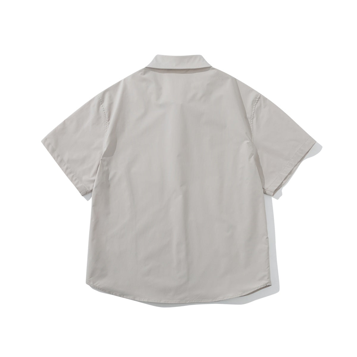 Back view of a light beige short-sleeve button-up shirt laid flat.