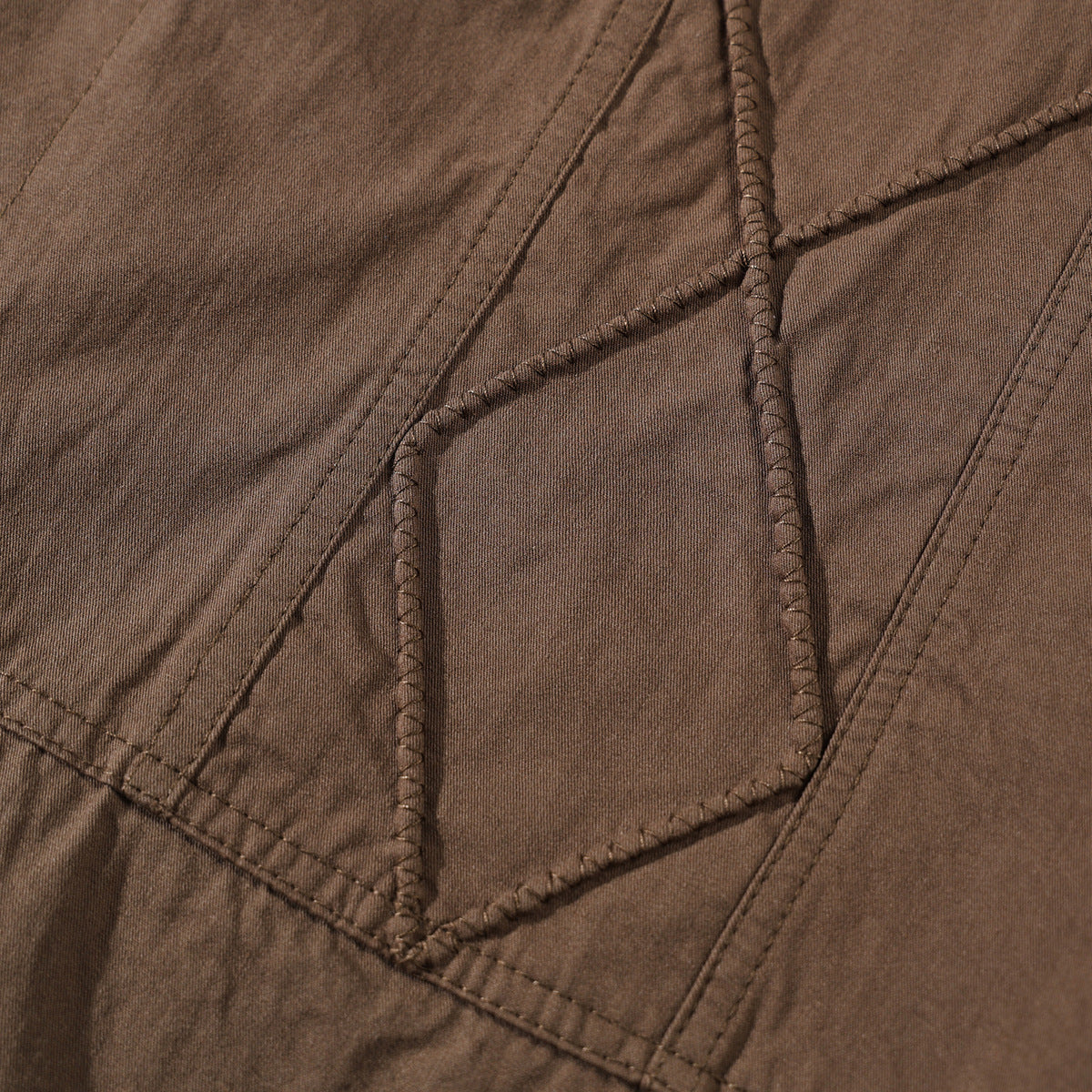 Close-up of brown shirt fabric with raised geometric stitching and seam details.