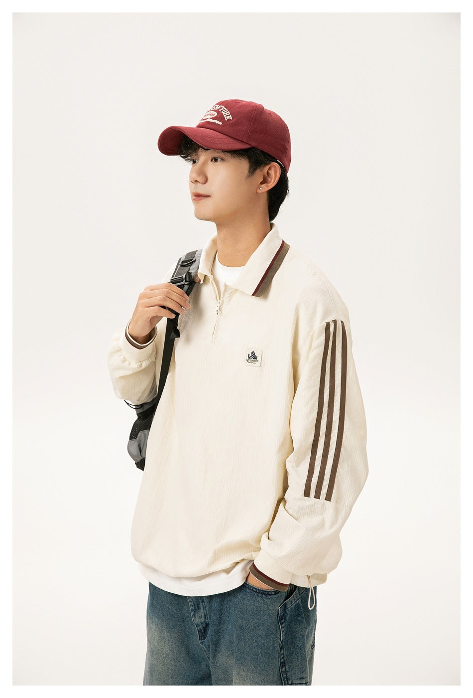 Three-quarter view of a model wearing a cream quarter-zip collared top with brown sleeve stripes and trim.