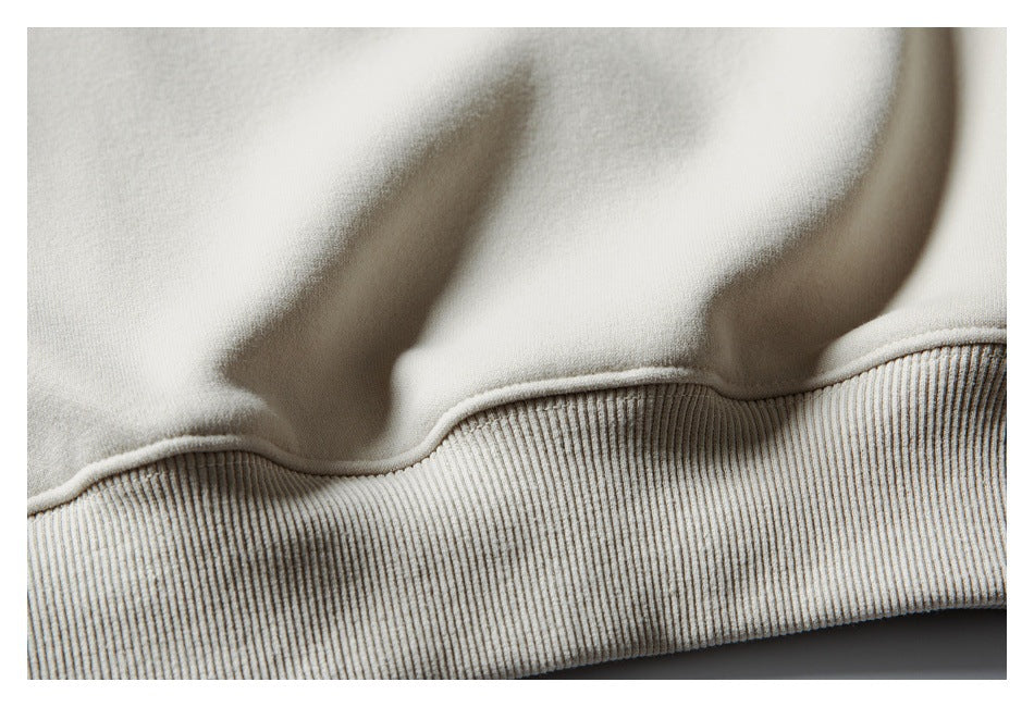 Close-up of an ivory sweatshirt's ribbed hem band and the seam joining it to the body.