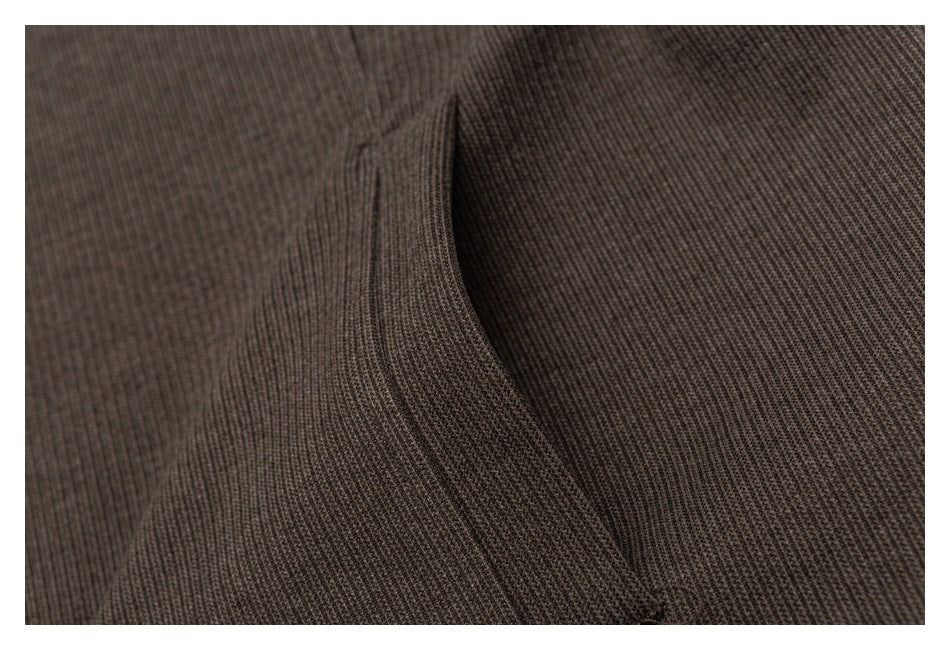 Close-up of a curved seam in the brown garment's fine textured fabric.