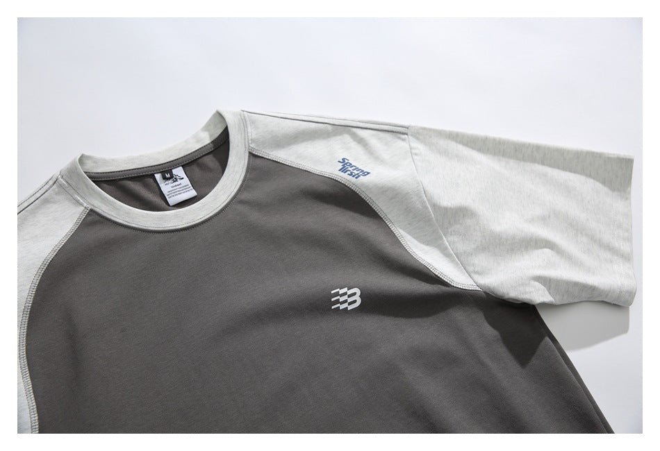 Close-up of the charcoal shirt chest with a small white emblem and light gray shoulder and sleeve panels.