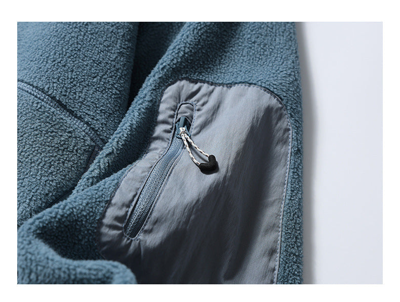 Close-up of a vertical zip pocket with a cord pull on the blue-gray fleece jacket.