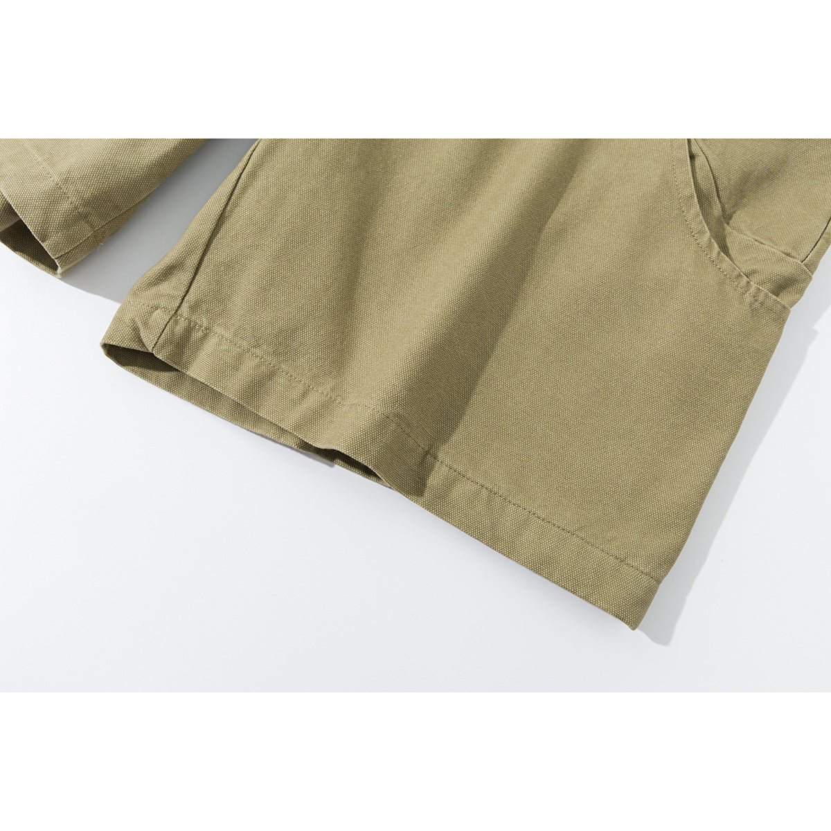 Close-up of khaki shorts showing the stitched leg hem and part of a curved pocket.