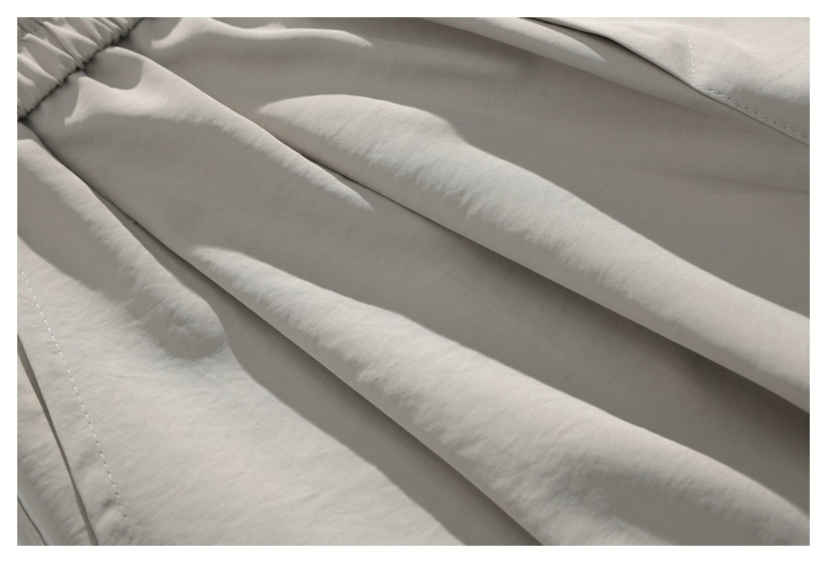 Close-up of the light beige trousers showing fabric folds and stitched seams.