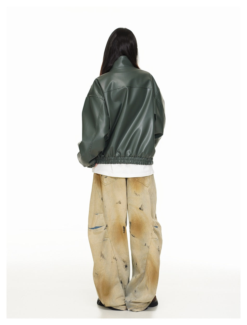 Rear view of a model wearing a dark green oversized jacket with gathered hem and loose tan distressed trousers.