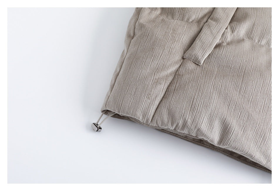 Close-up of a taupe-gray textured garment hem with an adjustable drawcord and metal toggle.
